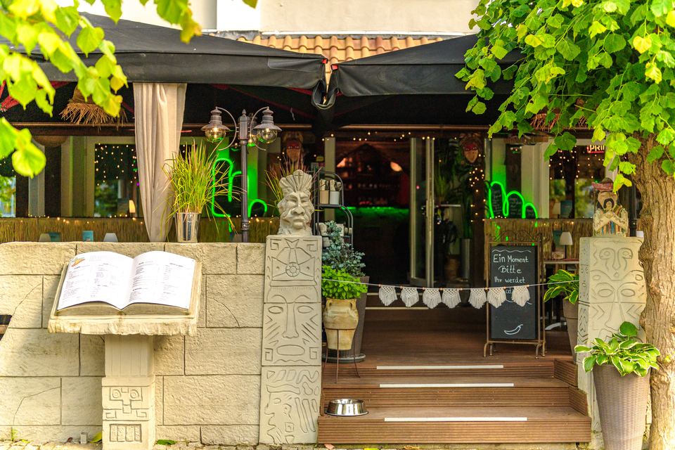 Eingang zur Terrasse mit Steinmauer und Speisekarte